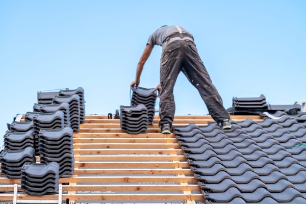 a craftsman installs a fired ceramic tile on the roof.